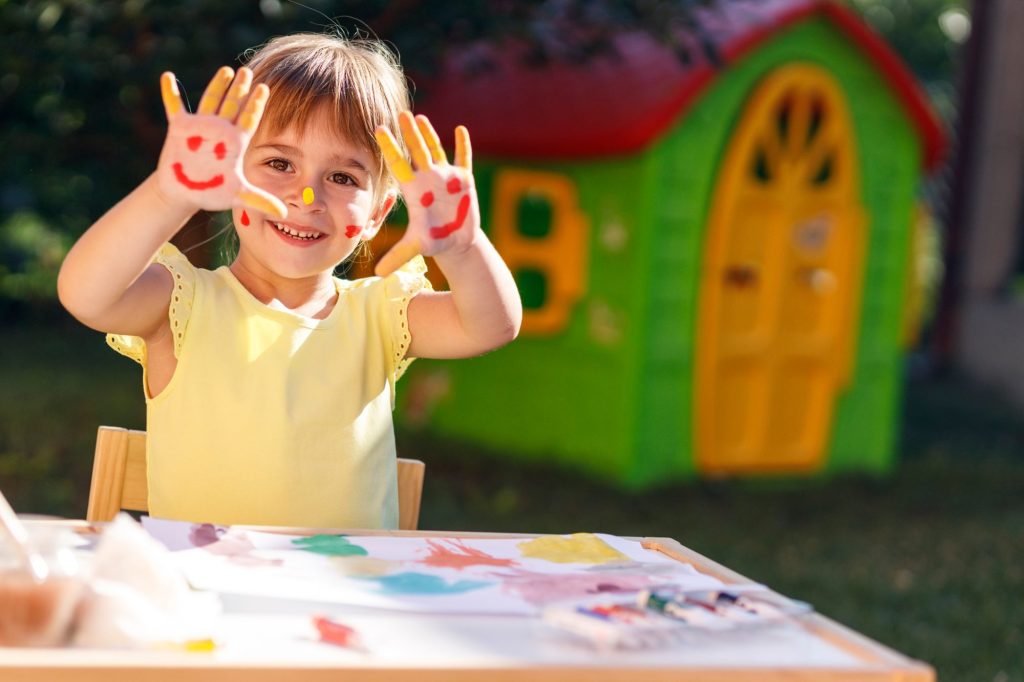 nina sonriendo con pintura en sus manos