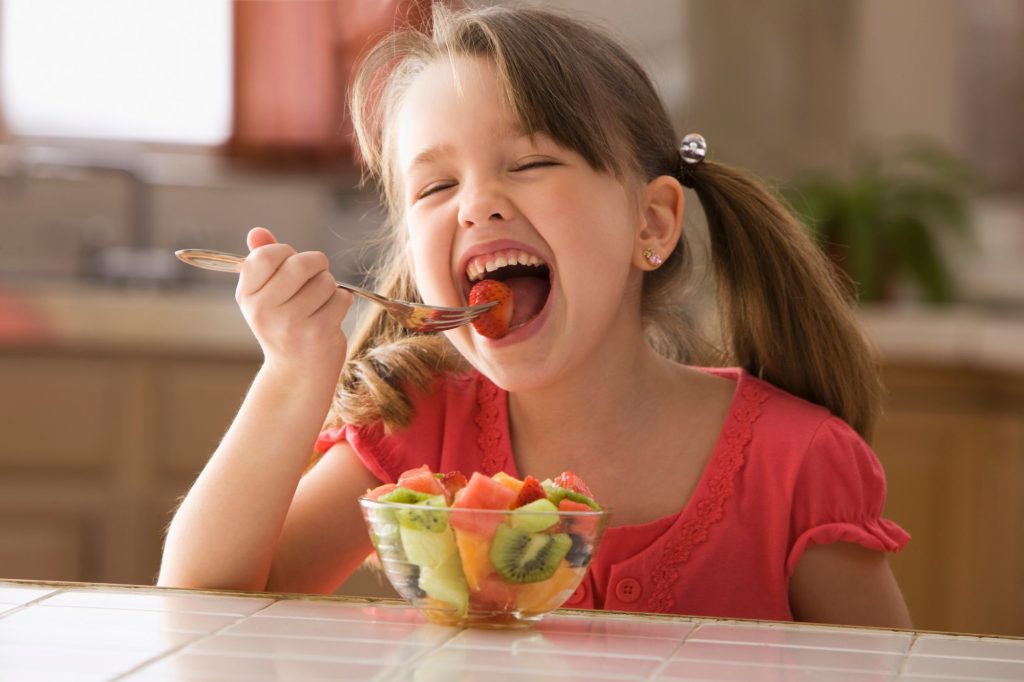 niña comiendo fruta en casa