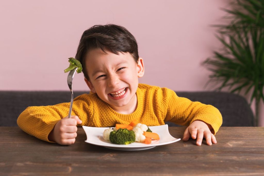 niño feliz comiendo verduras