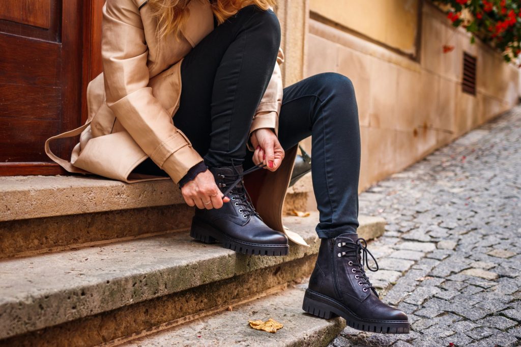 mujer rubia ajustando sus botas de cuero